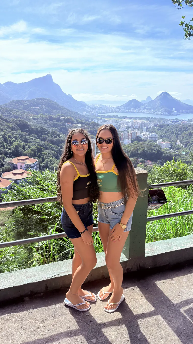 Três turistas posando juntas no mirante, com a Pedra da Gávea ao fundo.