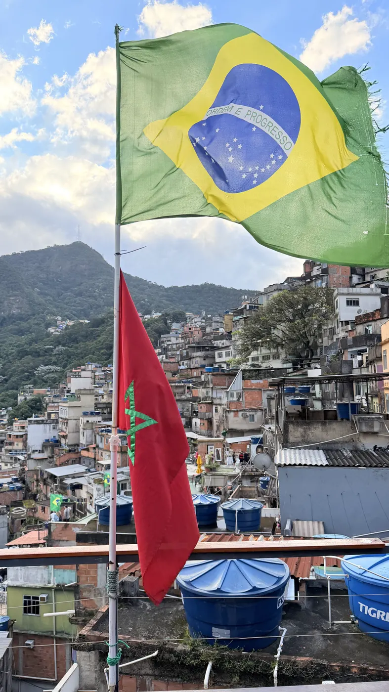 Bandeiras do Brasil e do Marrocos tremulando sobre os telhados da comunidade.