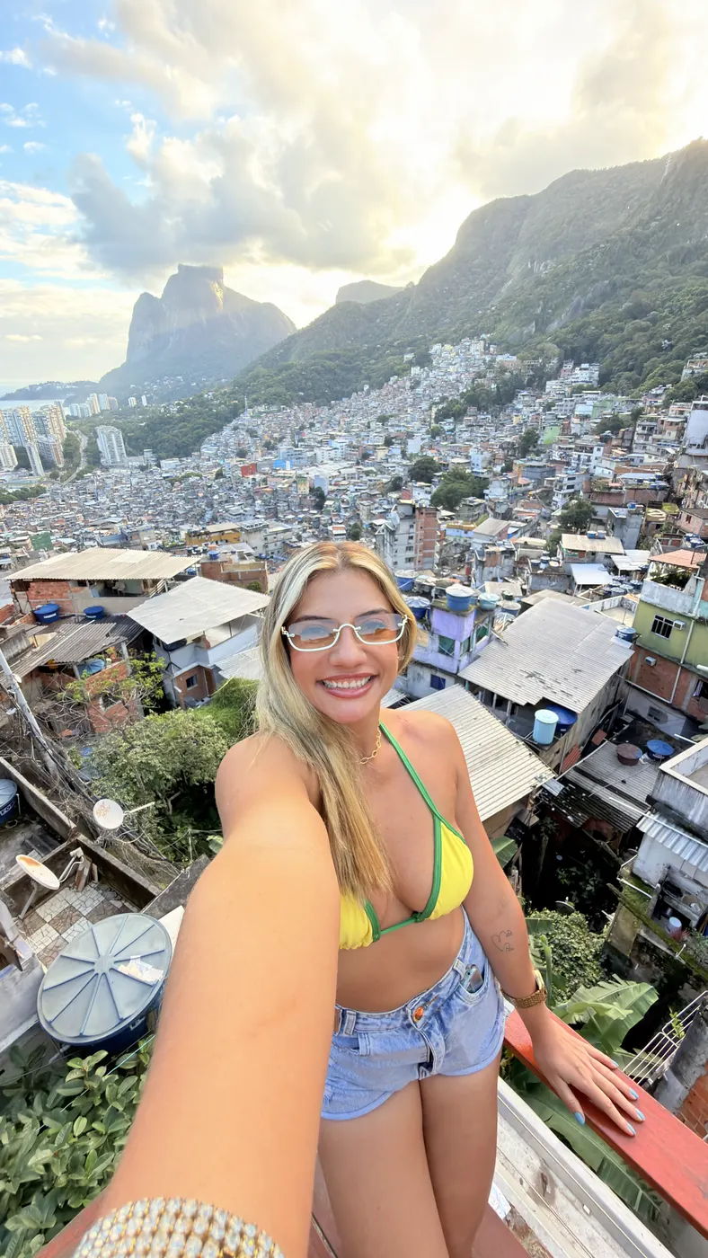 Selfie de turista no deck, com a Pedra da Gávea e o mar ao fundo.