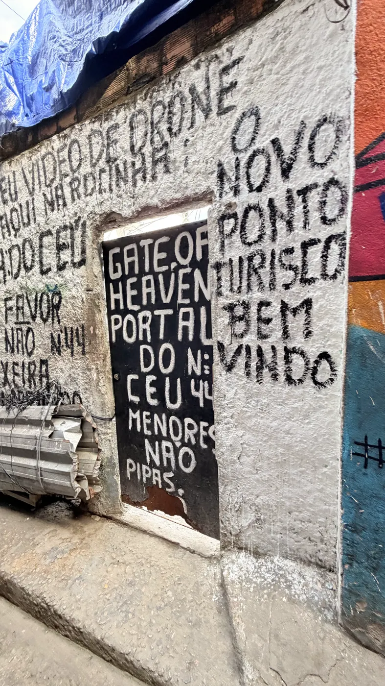 Muro grafitado da comunidade com a inscrição “Portal do Céu — Gate of Heaven”.